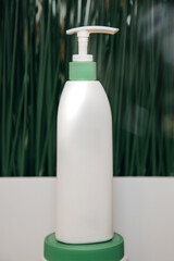 White cosmetic packaging, a jar with a dispenser on a green background. Front view