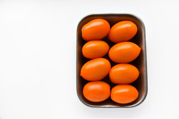 Orange ripe tomatoes on a plastic backing. Delicious tomatoes in a package from the store on a...