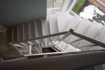 Fragment of a white wooden staircase. Steps, pillars, balusters, handrails made of ash.