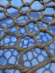 Black thick woven mesh on the blue background with a shadow from it.