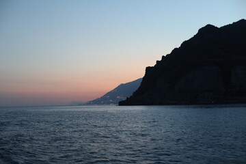 Naklejka premium Sunset view of the sea and mountain. Scenic view of the coast of island of the region. Evening landscape with mountains and sea. Dusk time lapse. Seascape with blue sky and clouds. Sea and rocks
