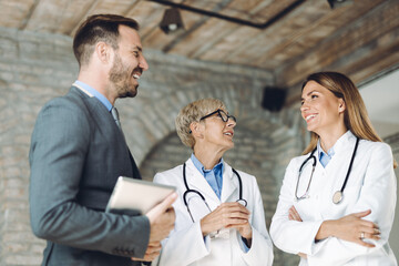 Happy mid adult businessman standing and discussing with  female doctors