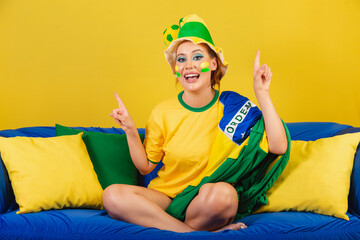 Caucasian woman, redhead, Brazilian soccer fan, Brazilian, on couch dancing