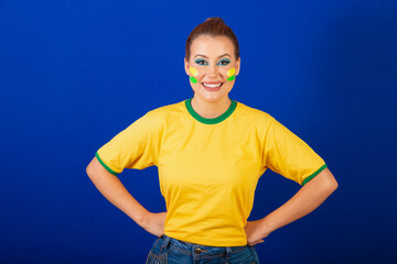 Caucasian woman, redhead, Brazil soccer fan, Brazilian, blue background, hands on waist