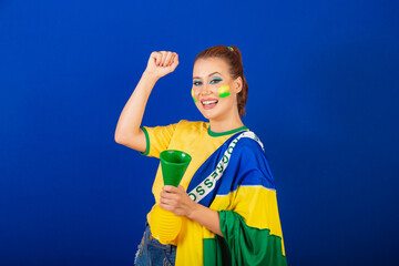 Caucasian woman, redhead, Brazil soccer fan, Brazilian, blue background, dancing with flag and horn