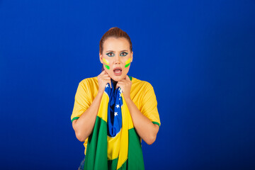 Caucasian woman, redhead, brazil soccer fan, brazilian, blue background, anxious and distressed...