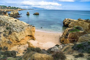 rocks and cliffs on the beach, ocean shore. sandy beach and rocks protruding from the sea in Praia de Sao Rafael. Sunny day, horizontal