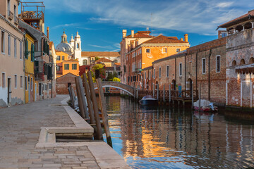 Fototapeta na wymiar Typical Venetian canal with bridge and church in the early morning, Dorsoduro, Venice, Italy