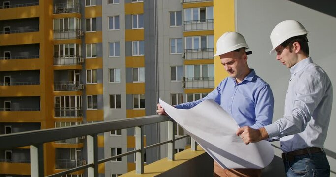 Man architect listens to colleague engineer about building of residential complex. Skilled builder explains to designer flats block finished drawings