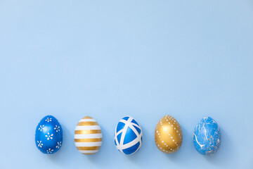 Frame of Easter golden decorated eggs in nest on blue background for web banner. Minimal easter concept. Happy Easter card with copy space for text. Top view, flatlay
