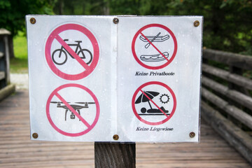 Prohibition signs on a wooden bridge on the shore of a lake in Austria.