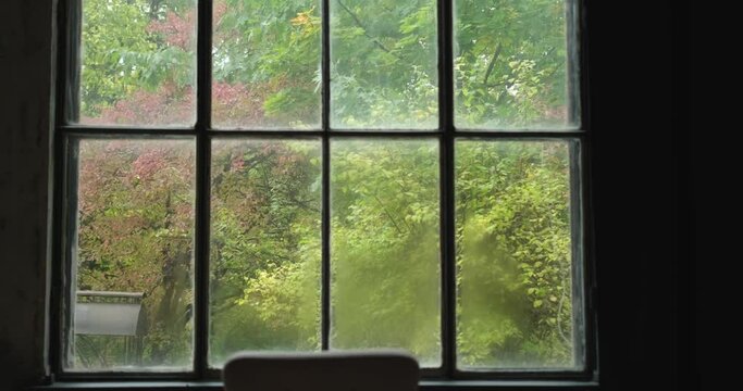Peace concept: chair in front of the huge window with garden or forest view in autumn colours. Windy and foggy weather outside. Fall season. High quality 4k video footage