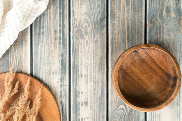 Empty wooden bowl on rustic gray wooden table surface with tray of spikelets and white towel. Copy space, top view