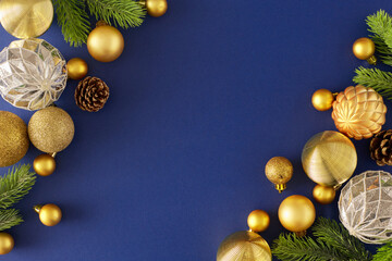 New Year eve concept. Creative flat lay composition of white gold christmas balls, spruce branches and fir cones on deep blue background with copyspace in the middle.