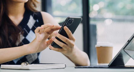 Woman hand using smart phone and laptop in outdoor nature park and sunset sky with bokeh light abstract background. Technology business and freelance working concept. Vintage tone filter color style.