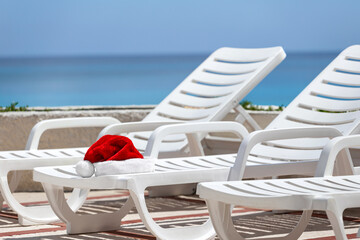 Santa Claus Hat on sunbed on caribbean sea background. Christmas and New Year vacation on the beach