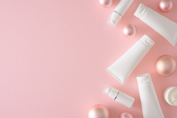 Winter season skin care concept. Creative layout made of white tubes, jars spray bottles and christmas baubles on pastel pink background with copy space. Minimal flat lay.