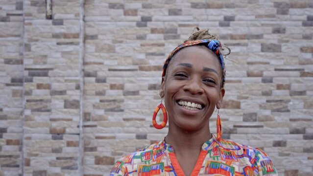mujer afro caribe&ntilde;a muy sonriente viendo a c&aacute;mara con unos aretes y una ropa muy colorida 