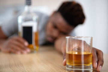 intoxicated man slumped on table holding glass