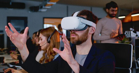 Close up of Caucasian man in VR glasses moving hands in air. Male in headset having virtual reality experience. Futuristic. Augmented. Robot on the background. Android. Humanoid.