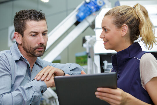 man and woman in warehouse discussing over tablet