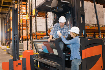 Fototapeta na wymiar woman passing note to forklift driver in warehouse