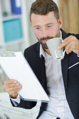 businessman holding clipboard and coffee cup