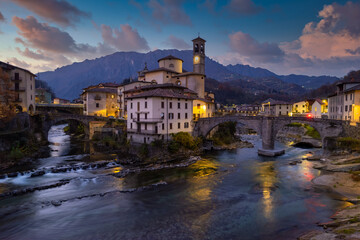 Fototapeta na wymiar Aerial villagescape - old church and crossing rivers with mountains backdrop, San Giovanni Bianco Village, Valbrembana, Bergamo, Lombardy, Italy