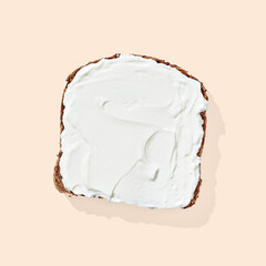Bread with cream cheese on orange pastel background