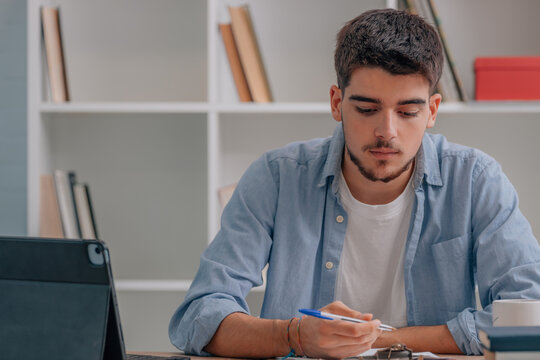 young man or student at desk filling in form or studying