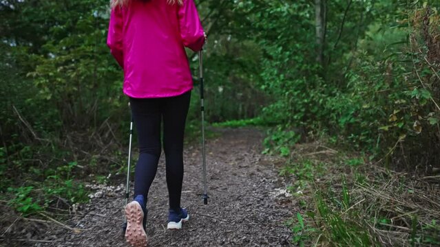 Woman with trekking sticks. Nordic walking.