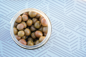 close up of olive jar for tasting in a picnic table outside. Veggie and vegetarian nutriment