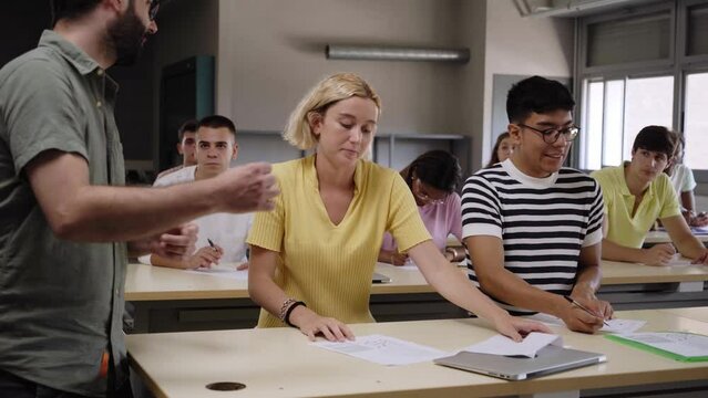 Young male teacher helping female student in class. The tutor helping his students by explaining the lesson and solving doubts. High quality 4k footage