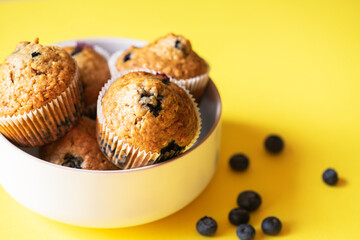 Blueberry muffins served on a white bowl on a yellow background. Close up. - 548052695