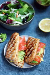 Salmon sandwich with avocado and lettuce.