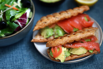 Salmon sandwich with avocado and lettuce.