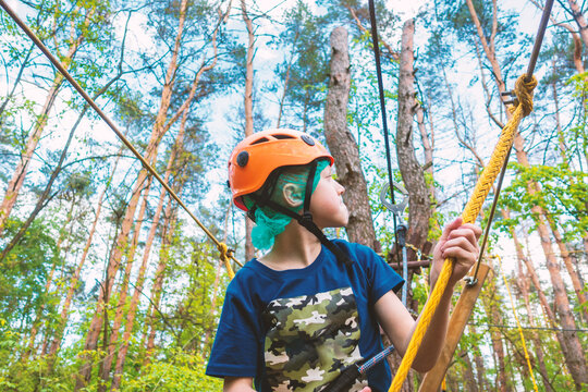 A boy in a helmet on a cable car in the forest overcomes obstacles