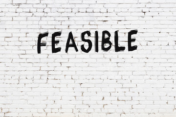 Inscription feasible painted on white brick wall - obrazy, fototapety, plakaty