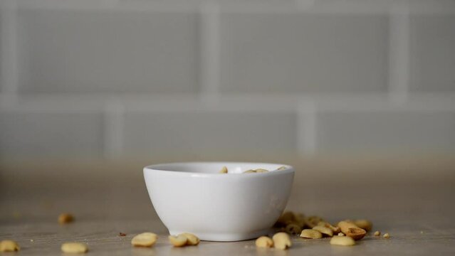 Closeup view  stock video footage of white small bowl full of tasty crispy organic salted toasted peanuts seeds. Man eating snacks with great appetite. Greedy and hungry man