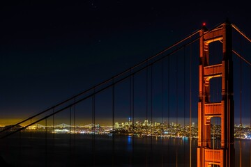 Scenic night shot of the Golden Gate bridge with decorative lights and skyline in the background