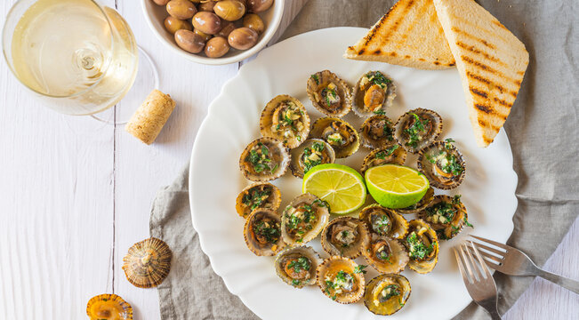 Patella, Limpets served with lime, olives and glass of white whine - traditional seafood of Tenerife and Madeira Islands.