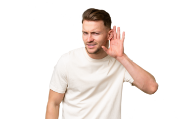 Young blonde caucasian man over isolated background listening to something by putting hand on the ear
