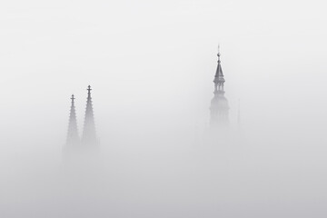 Silhouettes of towers of Prague Castle St. Vitus Cathedral with spires in the morning fog. Prague. Mist. Black and white. Monochrome.