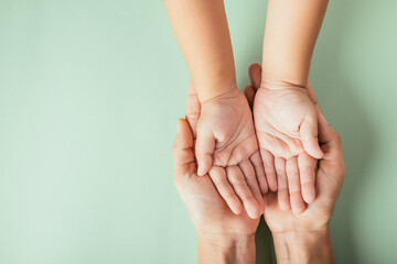 Closeup top view family hands stack palms studio shot isolated on green background, parents and kid holding empty free space on hand together, Gesture sign of support and love, Family and parents day