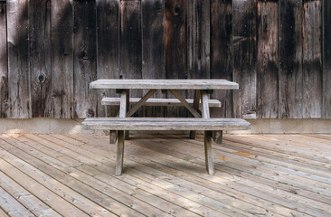 Old wooden bench and table on the background of wooden boards. Wood products. Rural background and seating area in the form of a bench and a table. Old weathered wood