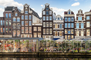 Amsterdam floating flower market and tall narrow historic canal houses along the Singel in the...