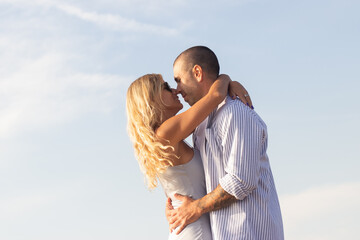 Couple in love at beach. Man with shaved head and woman in casual clothes looking at each other, touching with noses tenderly. Love, vacation, family concept
