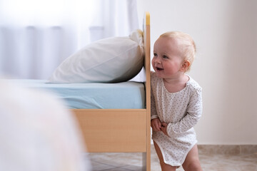 Caucasian baby girl playing hide and seek with her parents.