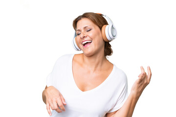 Fototapeta premium Middle-aged caucasian woman over isolated background listening music and doing guitar gesture