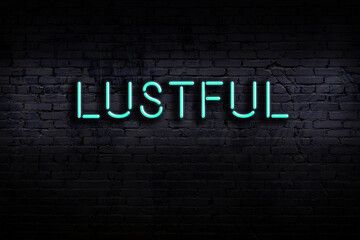 Neon sign. Word lustful against brick wall. Night view